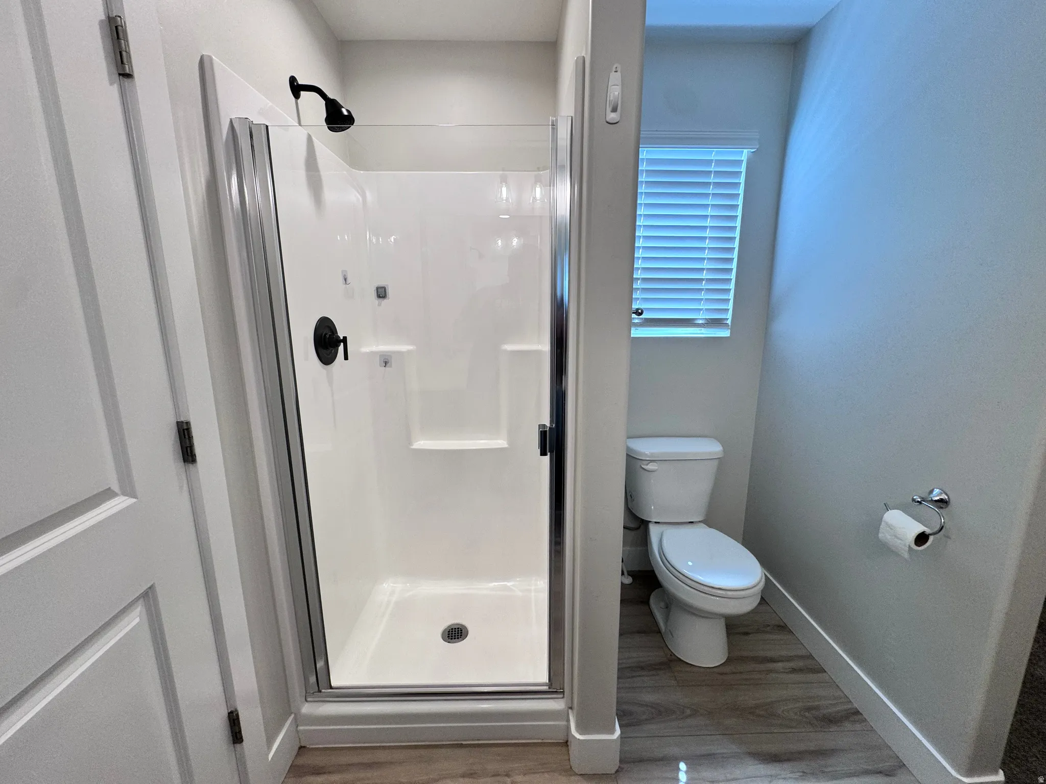 Full bath featuring a shower stall and light wood-type flooring