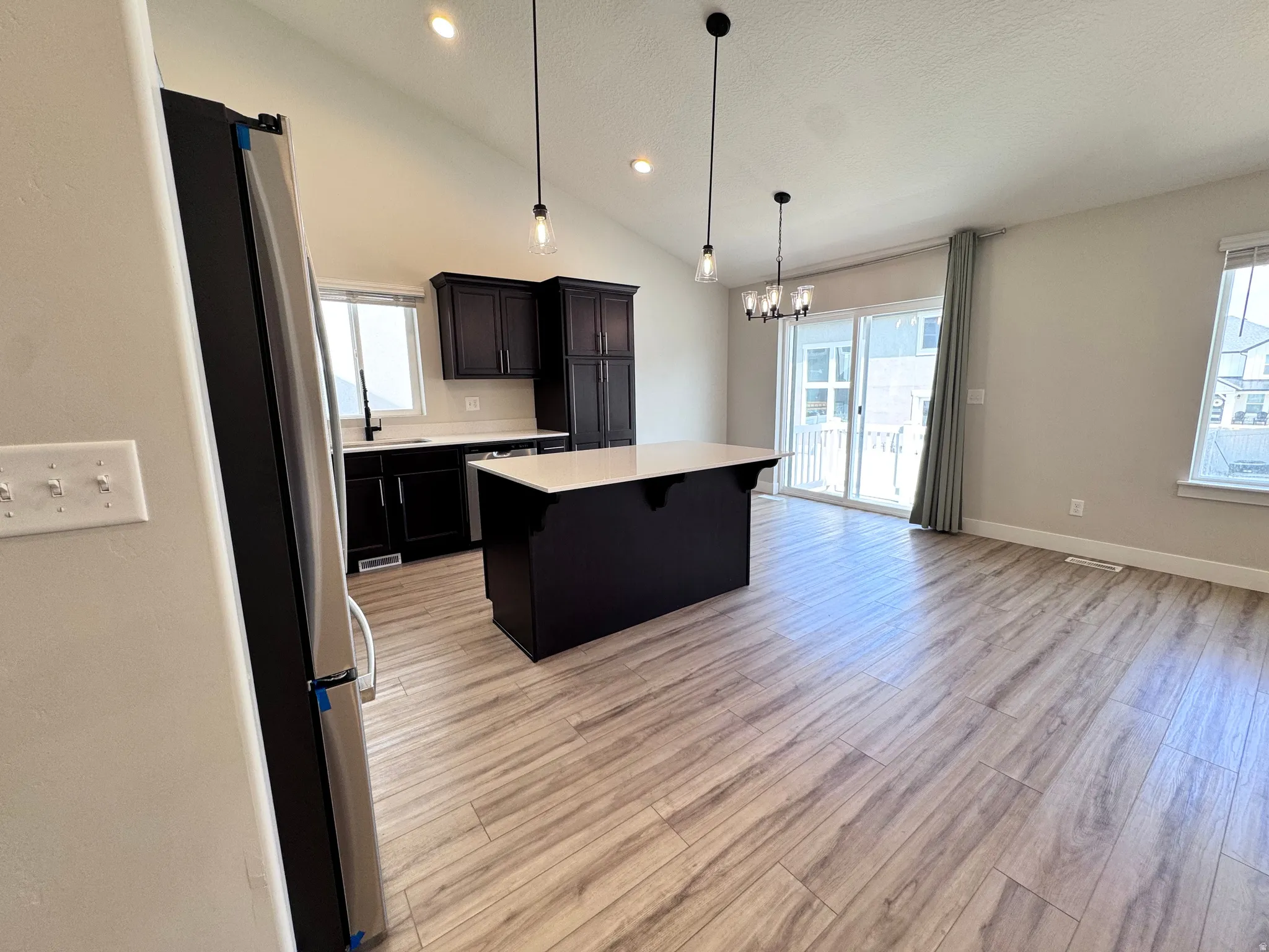 Kitchen with light countertops, a kitchen island, stainless steel appliances, a kitchen breakfast bar, and healthy amount of natural light