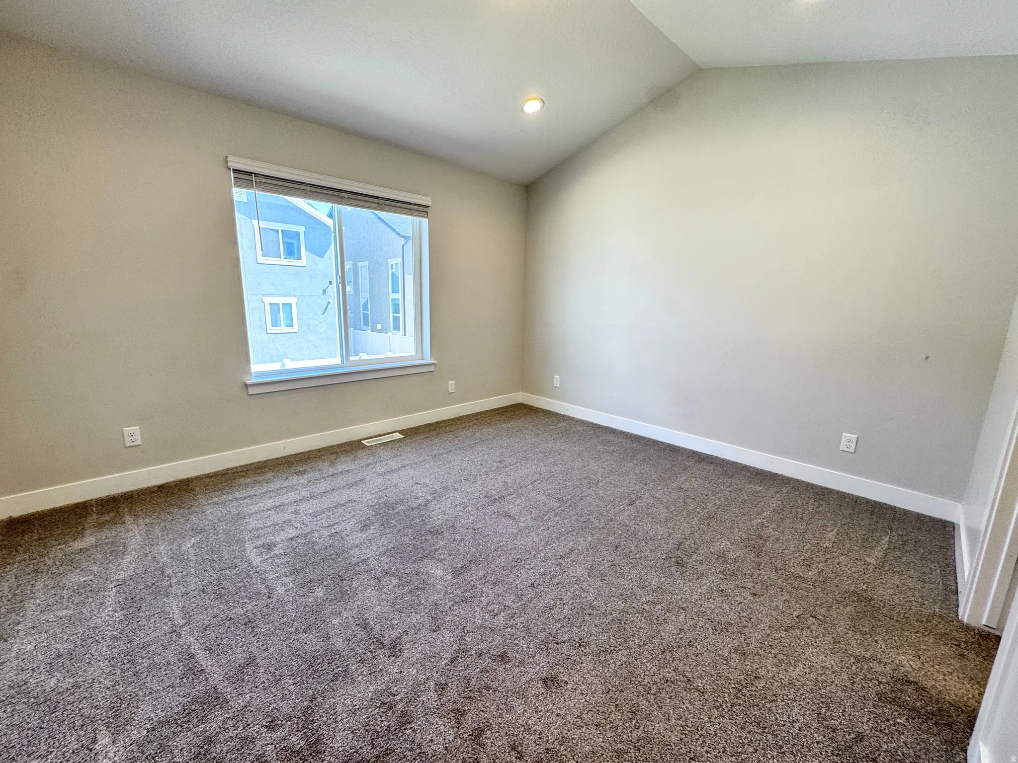 Spare room with dark colored carpet and lofted ceiling