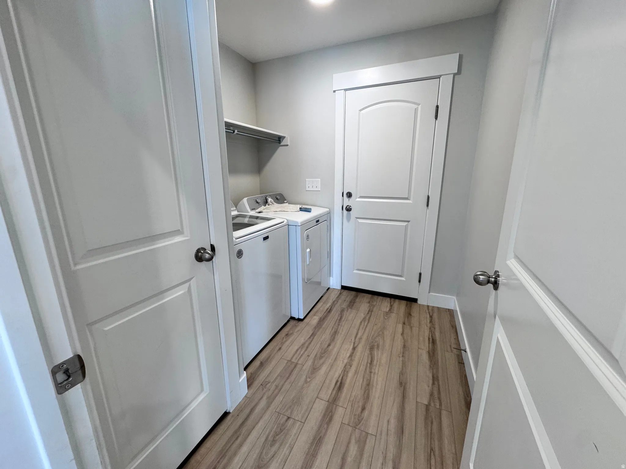 Laundry area featuring separate washer and dryer and light wood finished floors