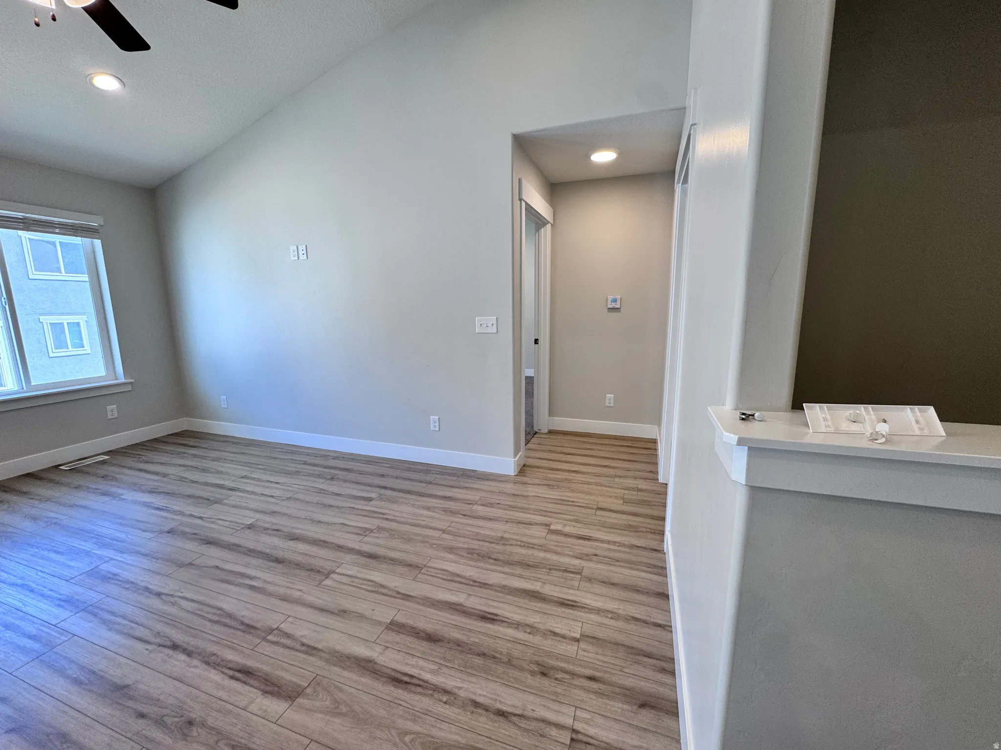 Unfurnished living room with a ceiling fan, light wood-style flooring, recessed lighting, and lofted ceiling