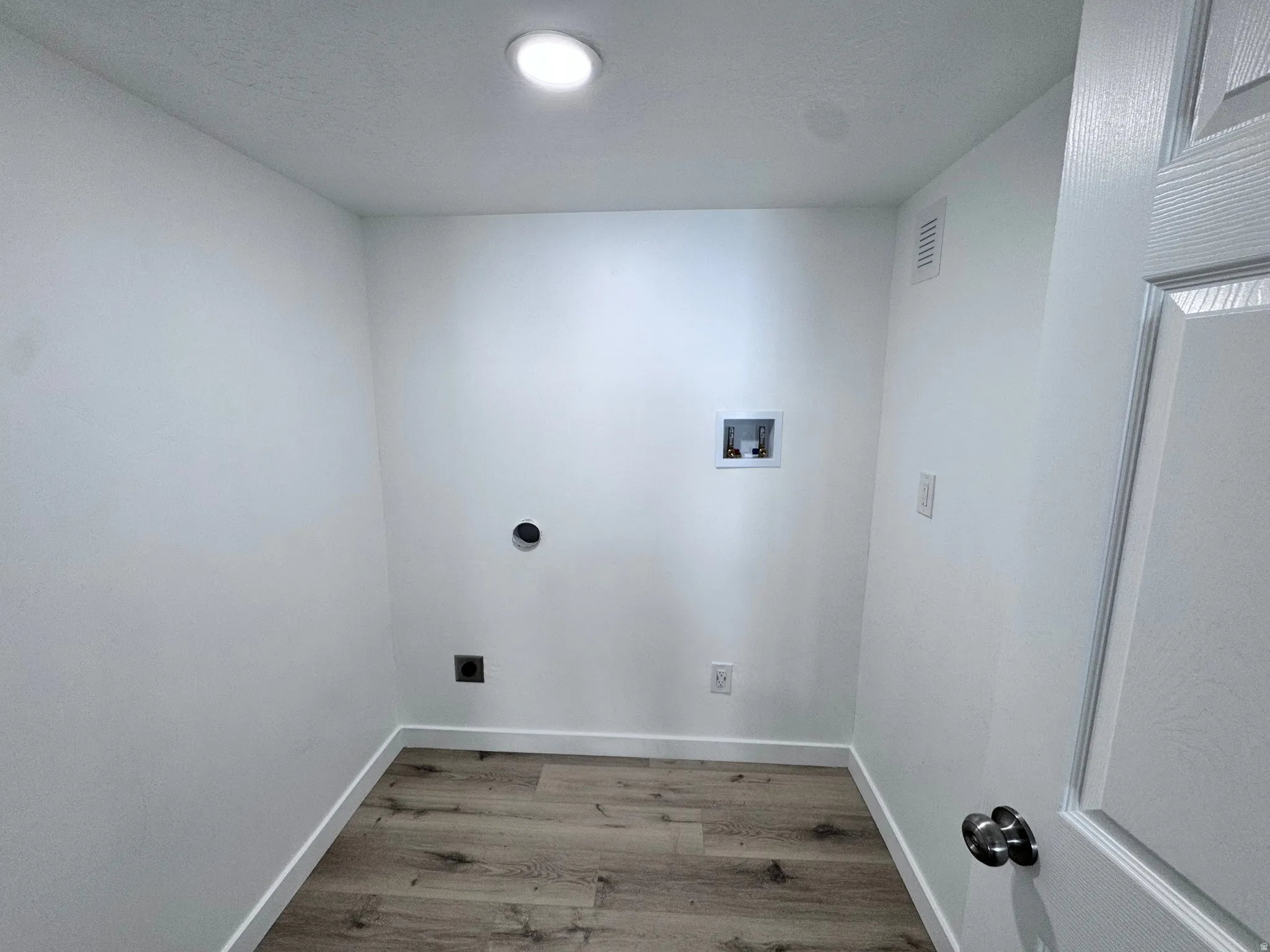 Laundry area with light wood-style flooring, hookup for a washing machine, and electric dryer hookup