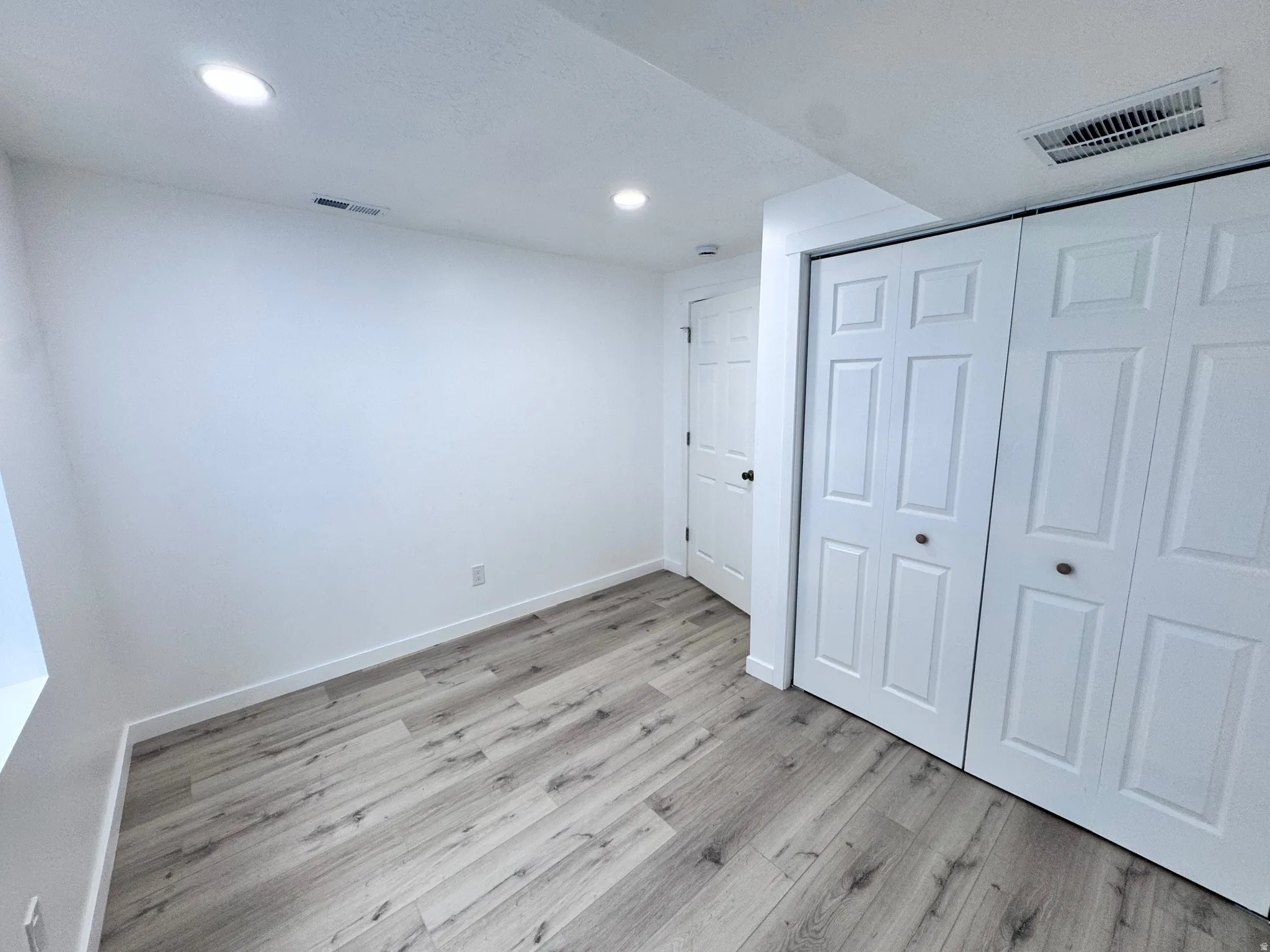 Unfurnished bedroom with light wood-style flooring, a closet, and recessed lighting