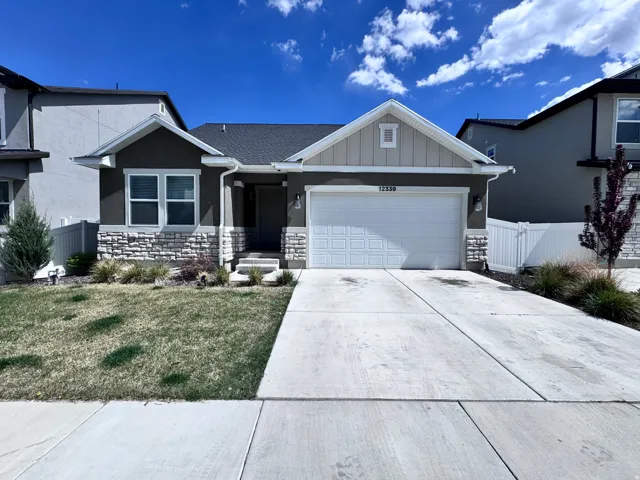 View of front of house with a garage, concrete driveway, board and batten siding, and stone siding