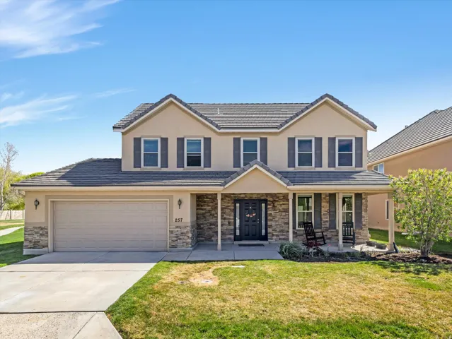 View of front facade with covered porch, a front lawn, concrete driveway, stucco siding, and a tile roof