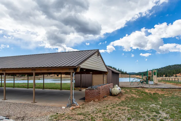 View of parking with a water view, a carport, and a playground