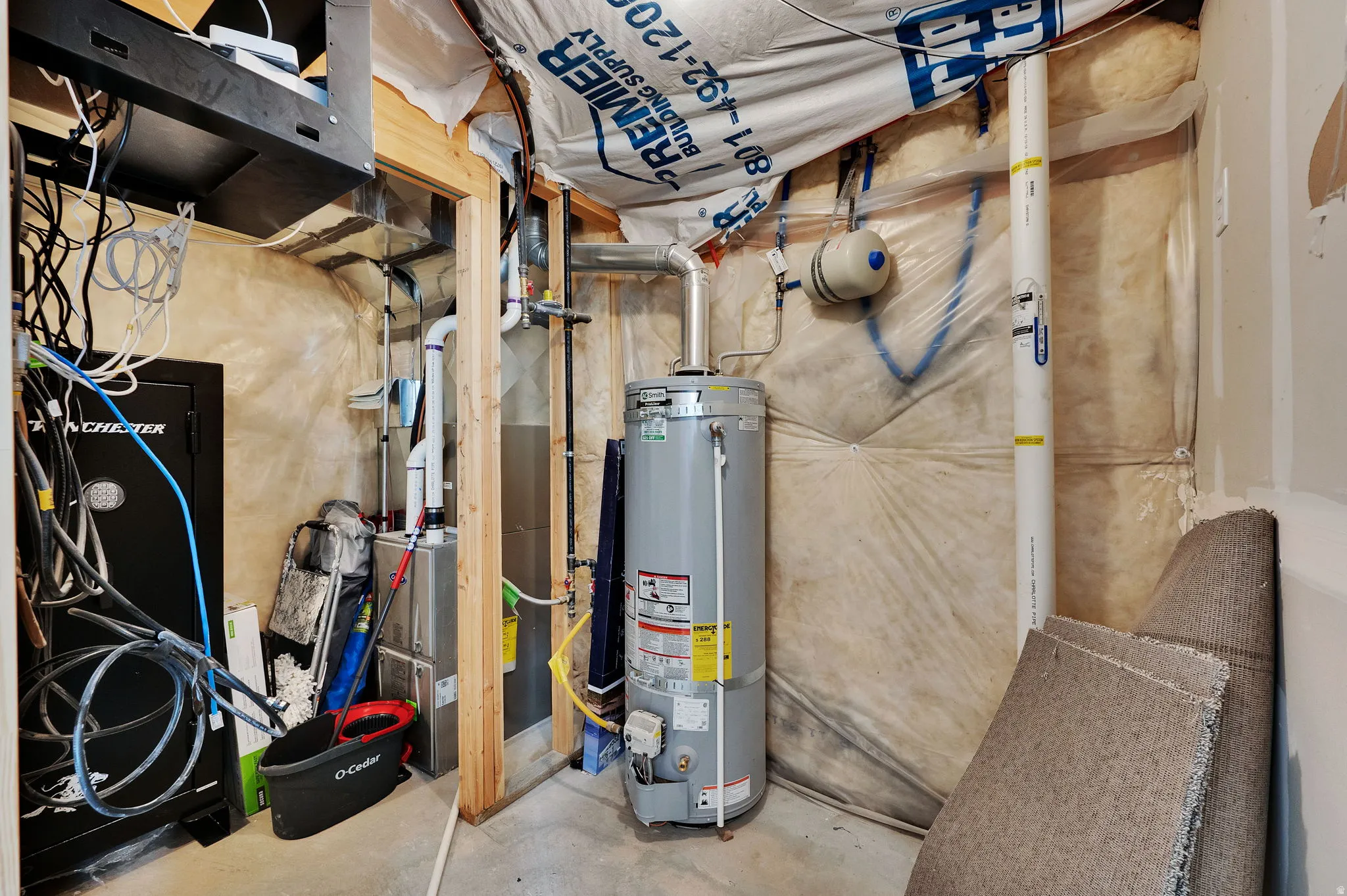 Utility room featuring strapped water heater and heating unit