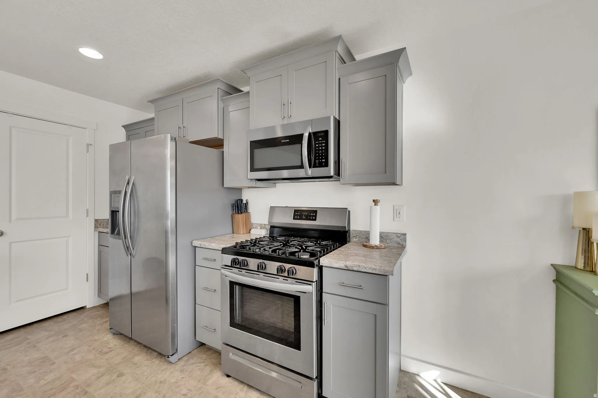 Kitchen with gray cabinetry, stainless steel appliances, light countertops, and light flooring