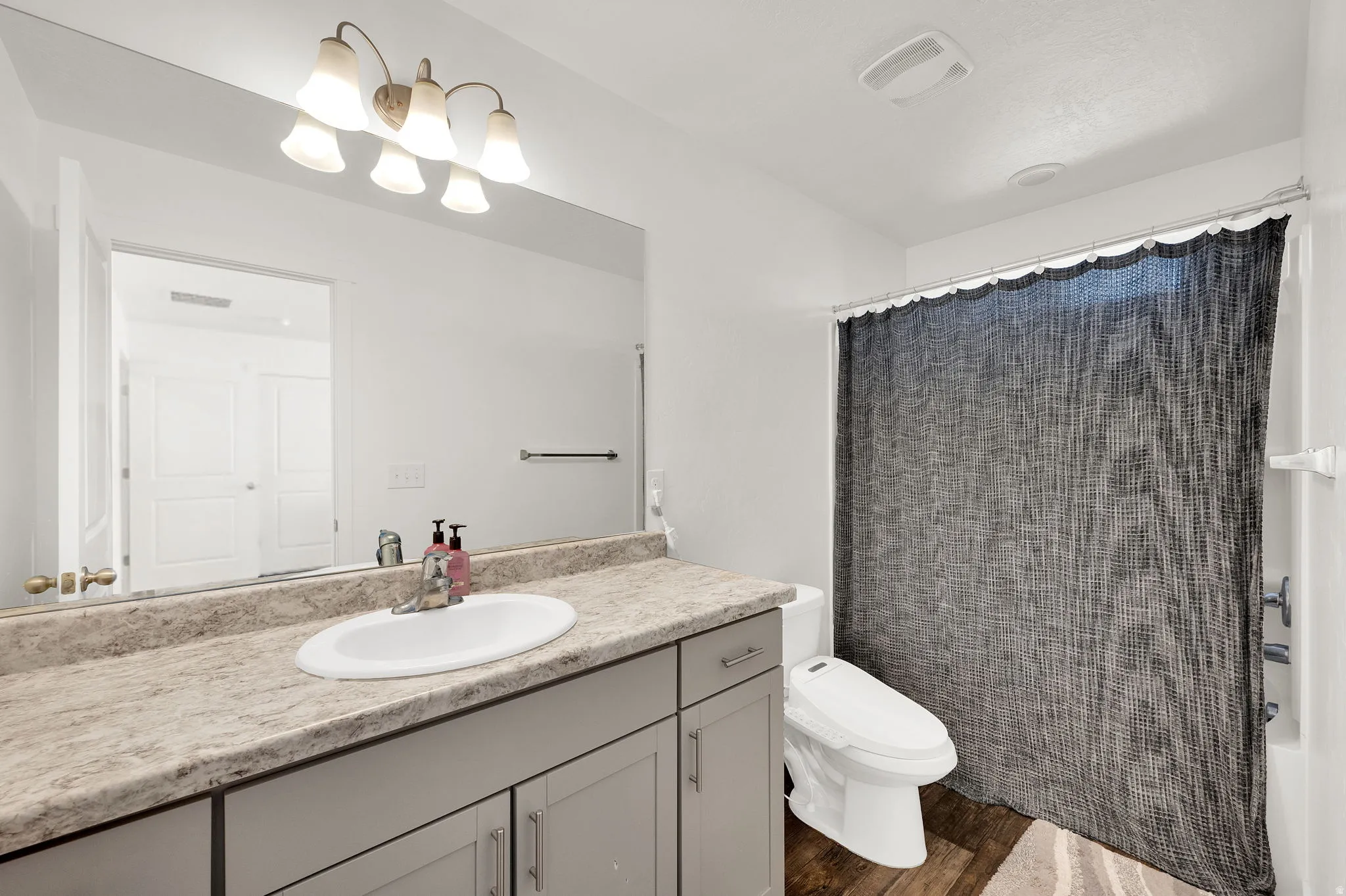 Bathroom featuring vanity, wood finished floors, and shower / bath combo with shower curtain