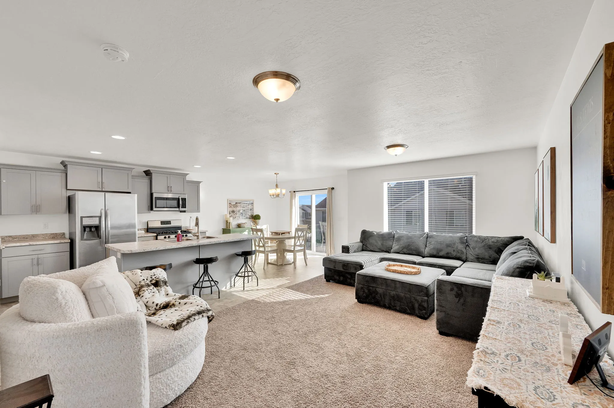 Living room with light carpet, a chandelier, and a textured ceiling