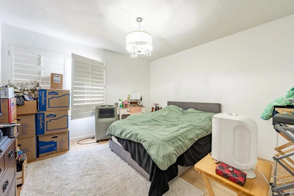 Bedroom featuring light wood-style floors, a textured ceiling, and a chandelier