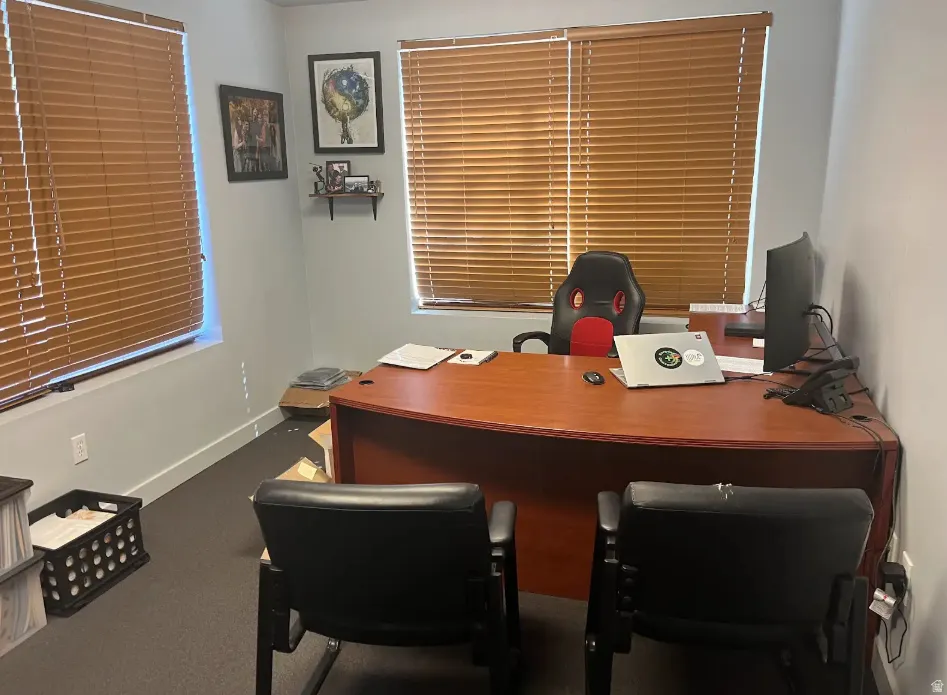 Office space featuring baseboards and dark carpet