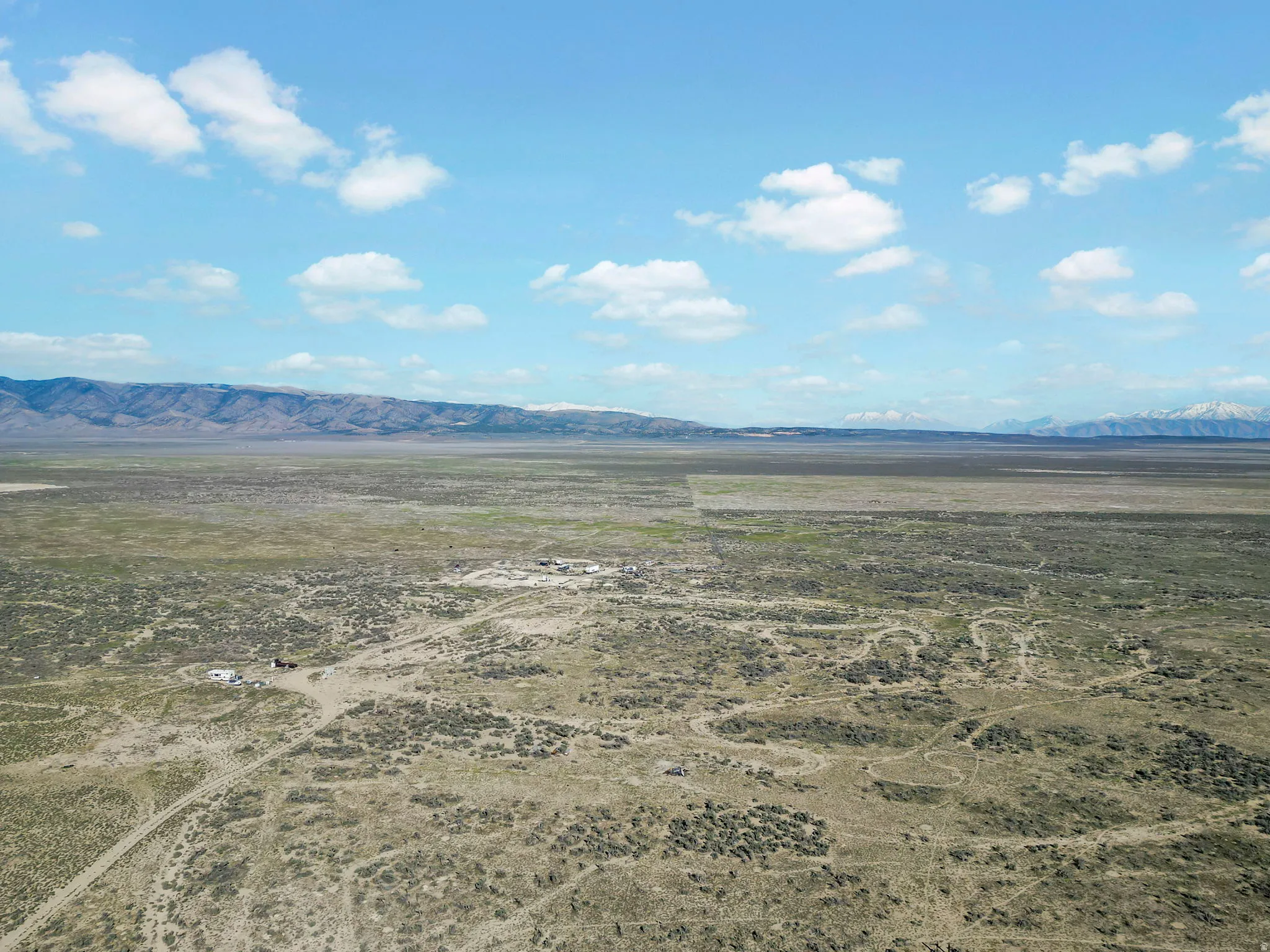 Expansive desert landscape featuring natural vegetation and distant mountain ranges with snow-capped peaks