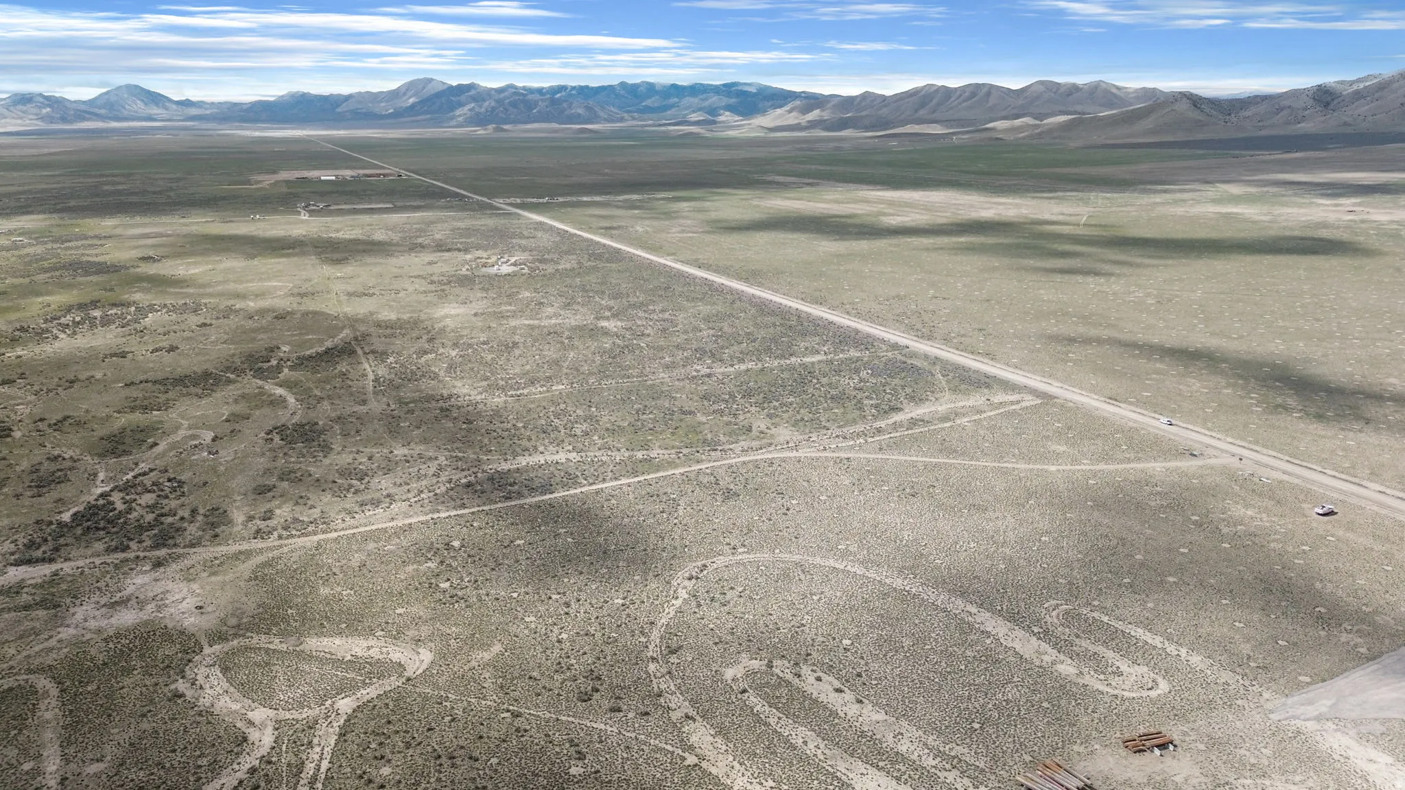 Expansive desert landscape featuring a long, straight road traversing the terrain