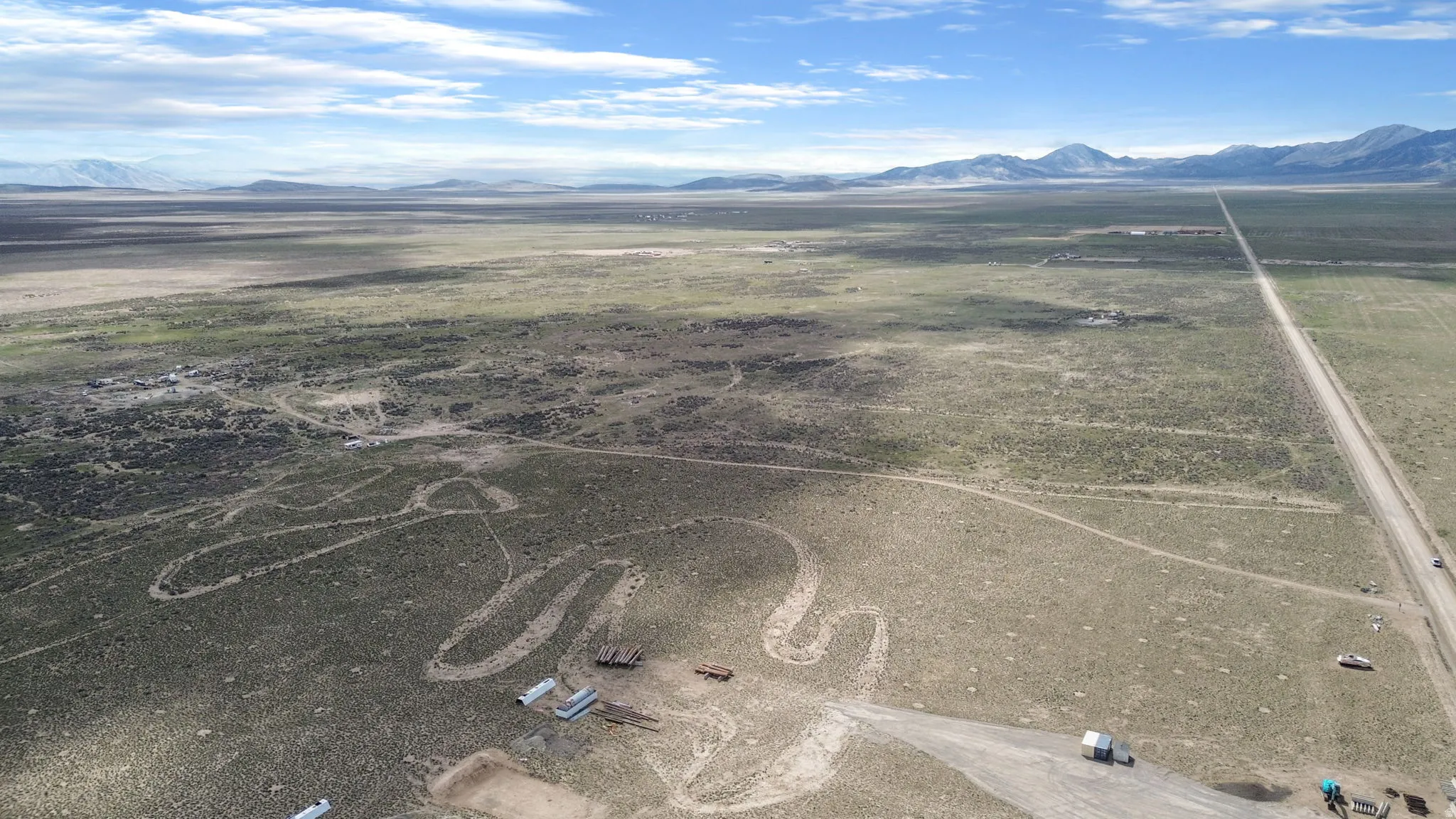 Expansive landscape featuring distant mountains and a long, straight road