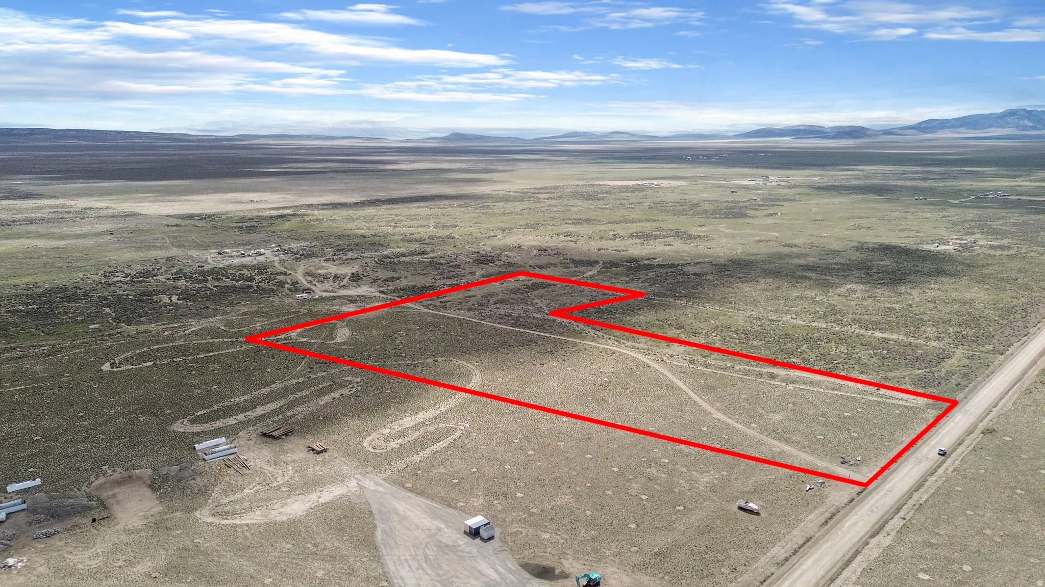 Expansive arid land parcel featuring a visible boundary outline, bordered by a dirt road