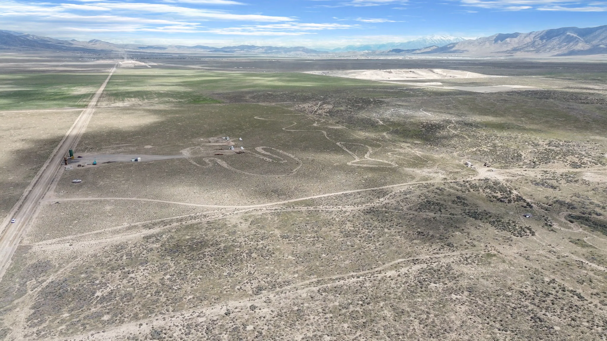 Expansive desert landscape featuring a long, unpaved road traversing the terrain
