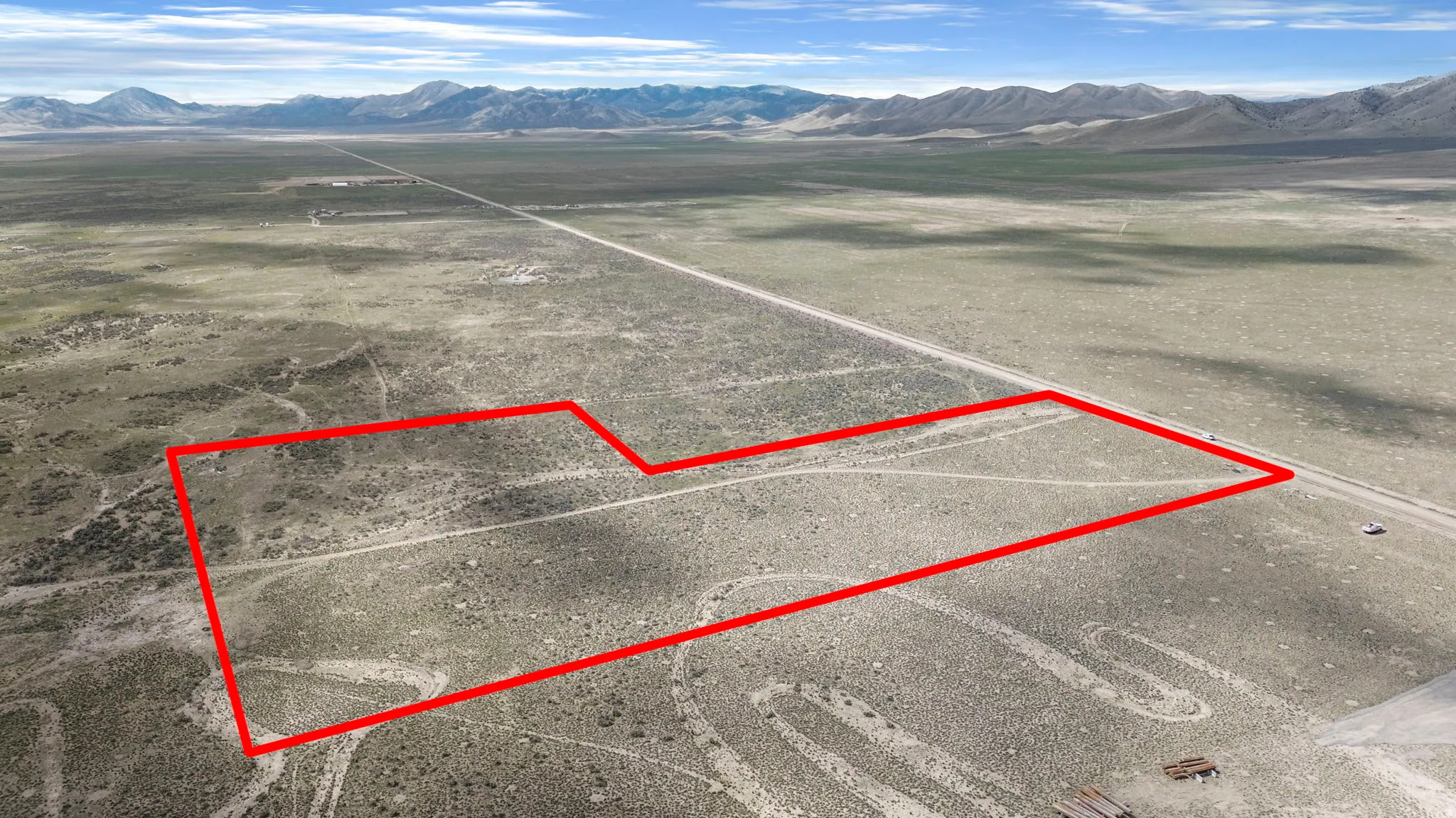 Expansive undeveloped land featuring a distinct boundary highlighted in red, extensive natural ground cover, and distant mountains