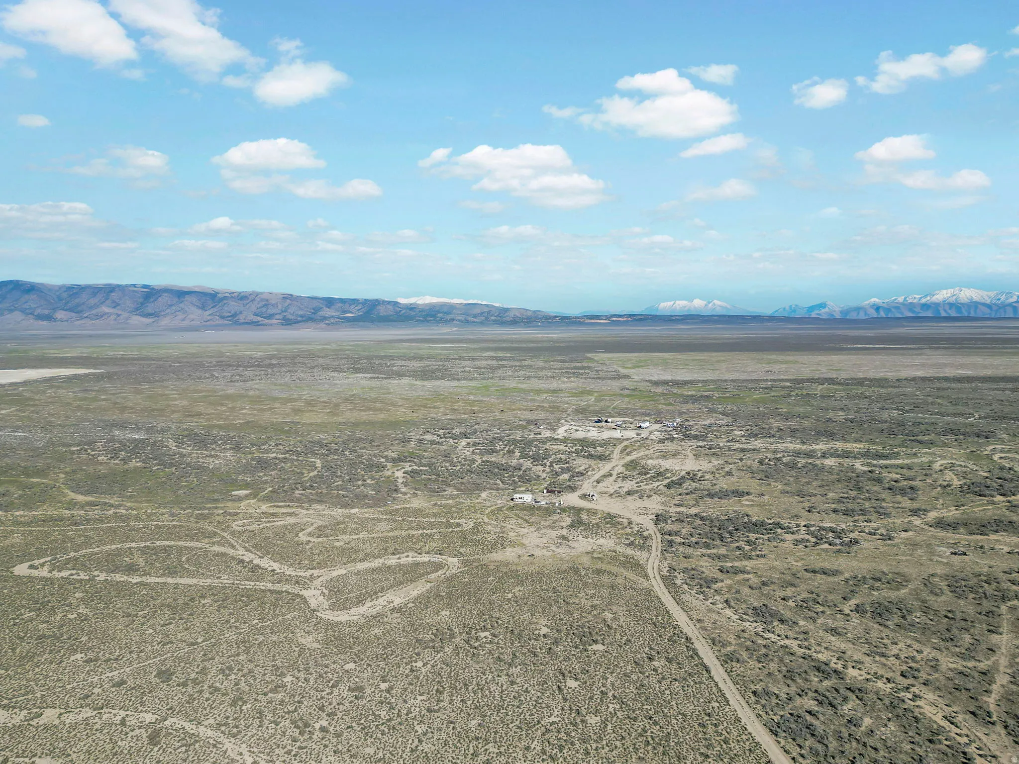 Expansive desert landscape featuring distant mountains and a clear sky with scattered clouds