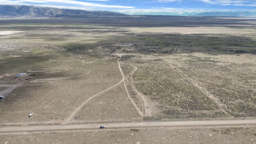 Expansive high desert landscape featuring a prominent road frontage, natural terrain, and distant mountain ranges