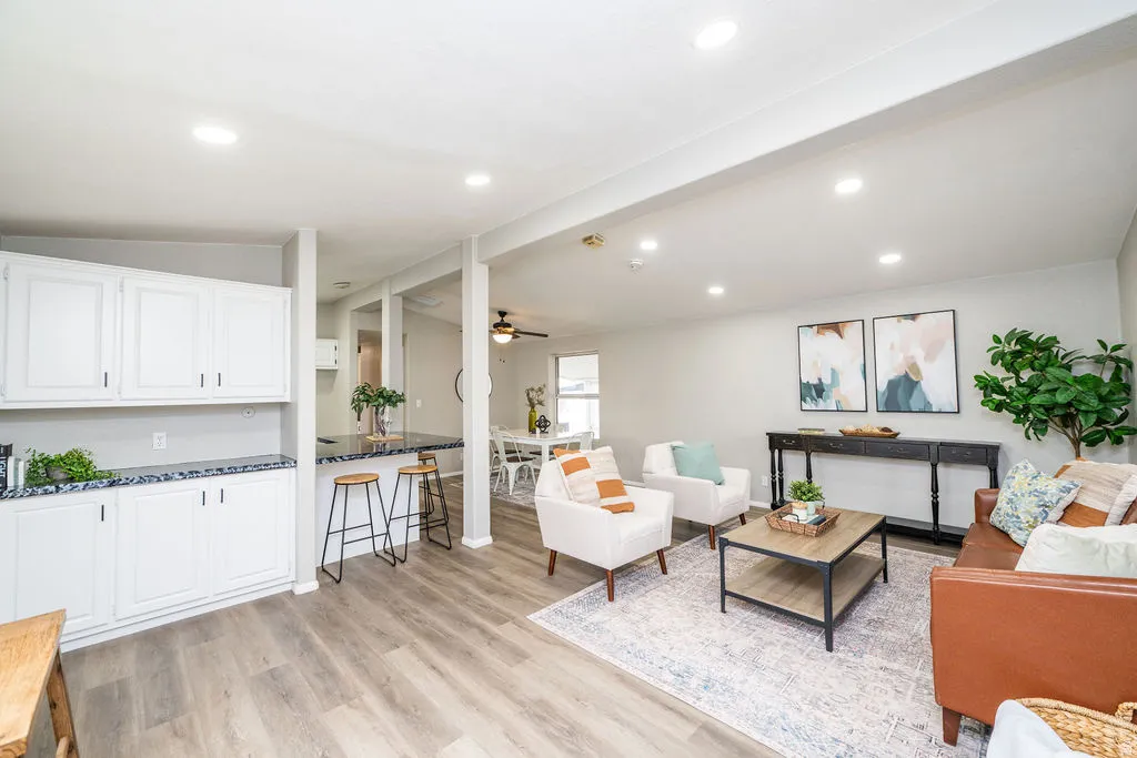 Living area featuring vaulted ceiling, light wood finished floors, a ceiling fan, and recessed lighting