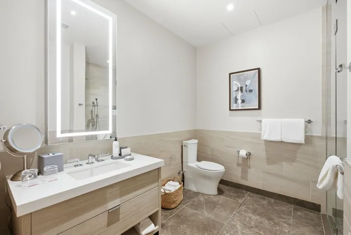 Bathroom featuring vanity, a tile shower, tile walls, and wainscoting
