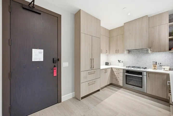 Kitchen featuring light wood finish cabinetry, modern cabinets, stainless steel appliances, and backsplash