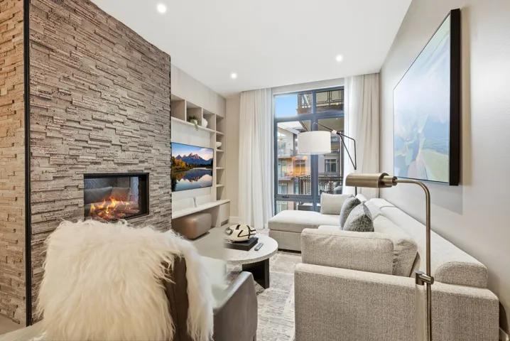 Living area featuring built in features, a stone fireplace, recessed lighting, and expansive windows