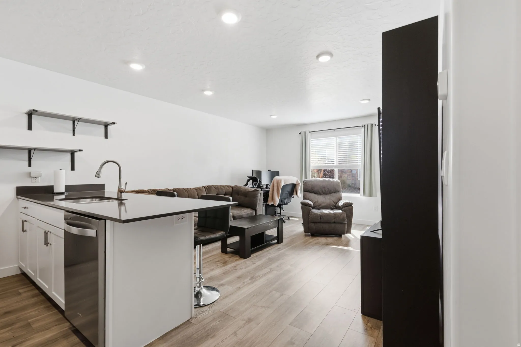 Kitchen featuring a peninsula, open shelves, open floor plan, a kitchen breakfast bar, and white cabinets