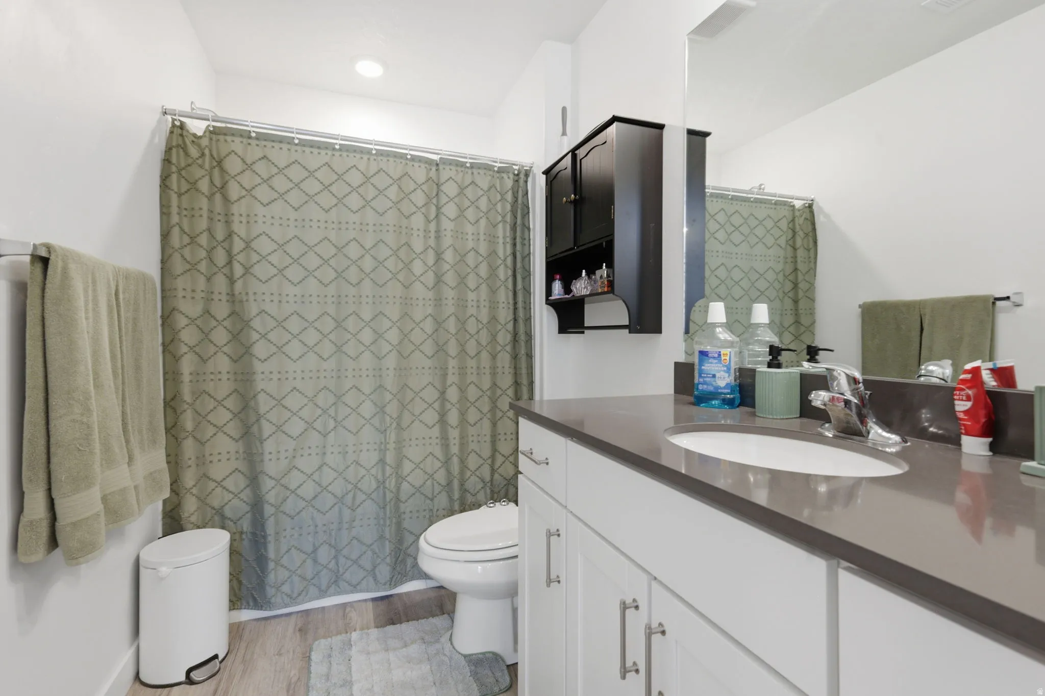 Full bath featuring vanity, curtained shower, and light wood-type flooring