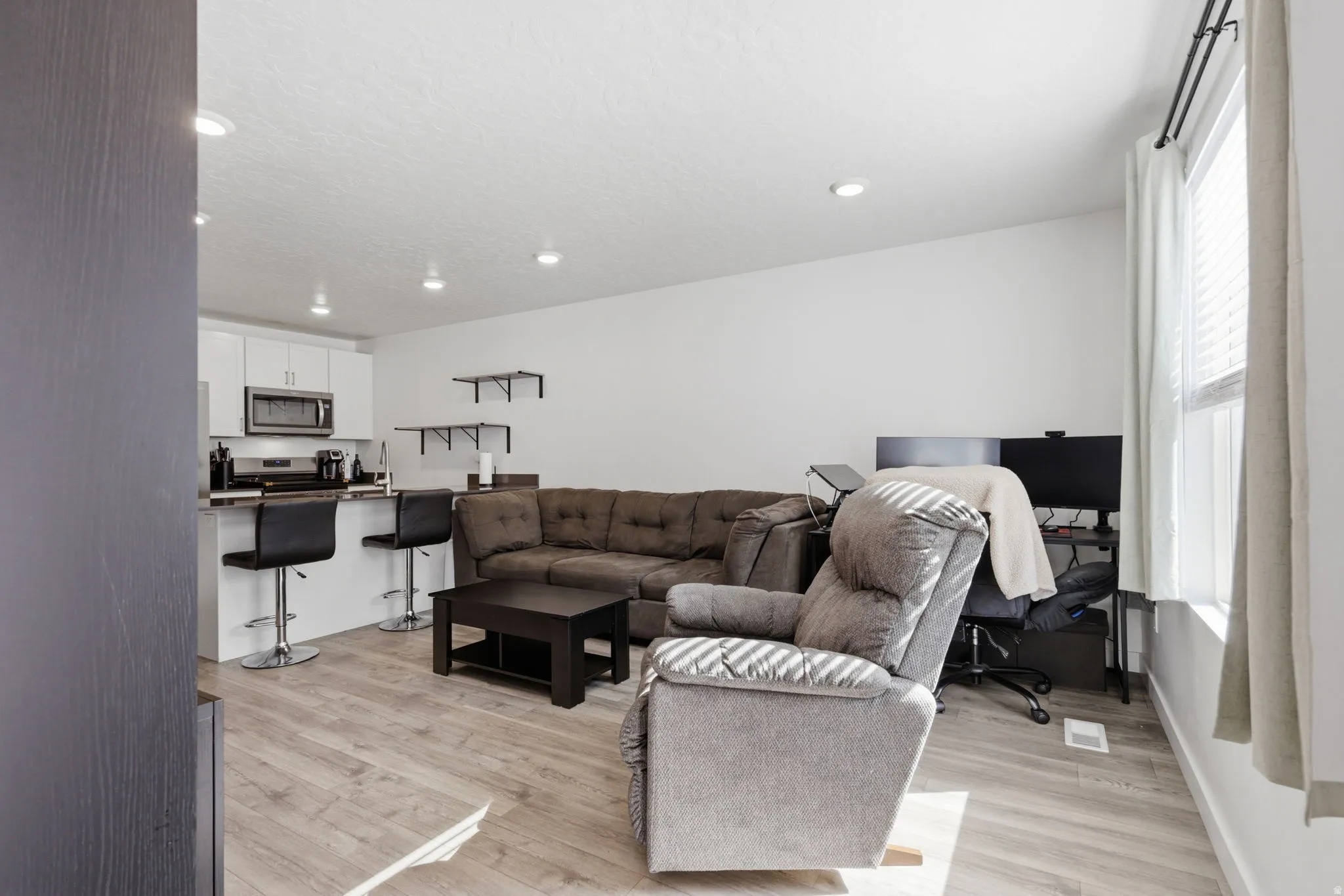 Living room featuring light wood finished floors, an office area, and recessed lighting