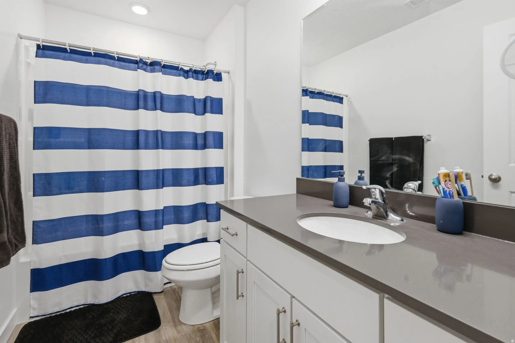 Full bath with vanity, light wood-type flooring, and curtained shower