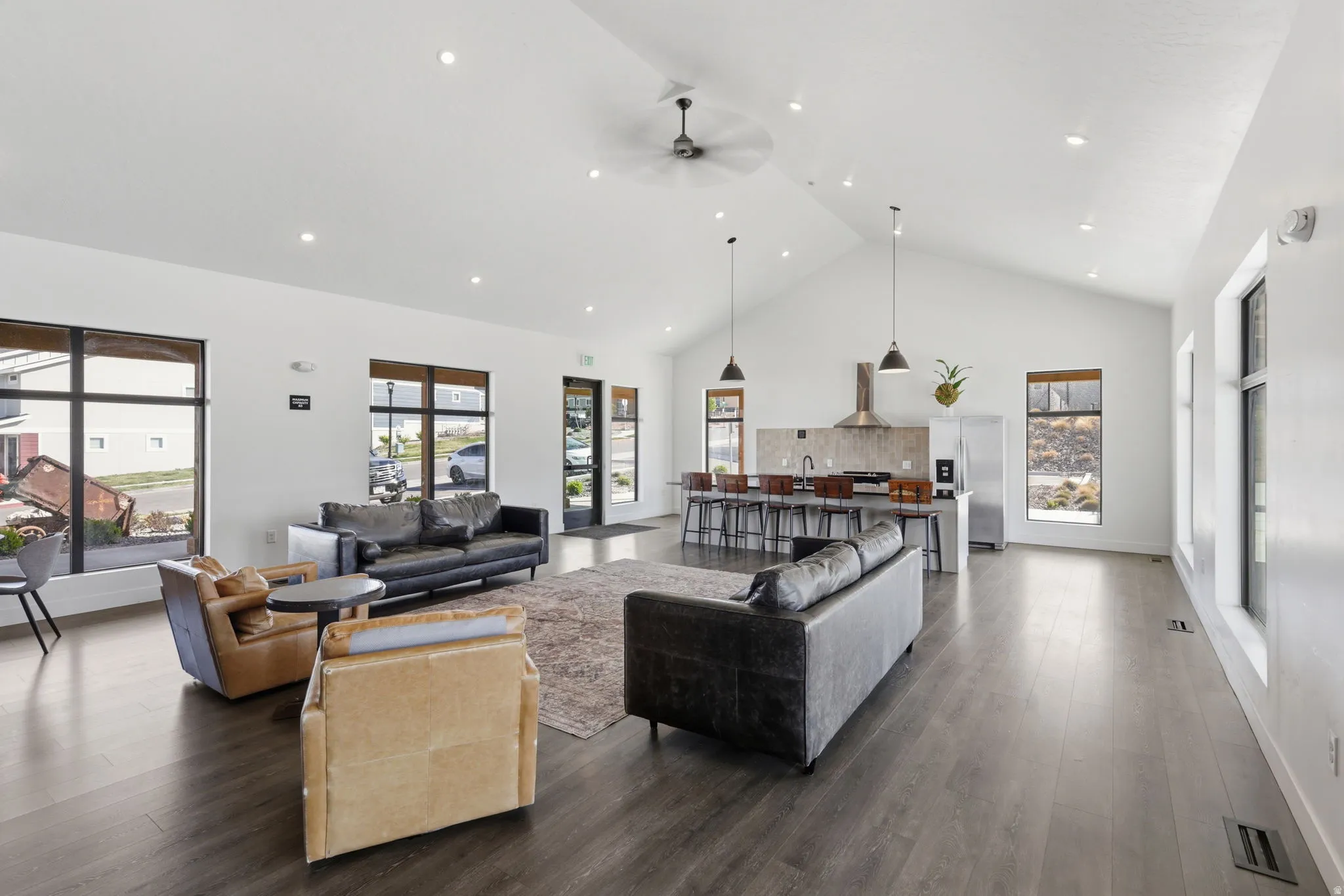 Living room with a high ceiling, a ceiling fan, wood finished floors, plenty of natural light, and recessed lighting