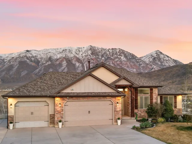 View of front of house featuring a garage, concrete driveway, a mountain view, and stone siding