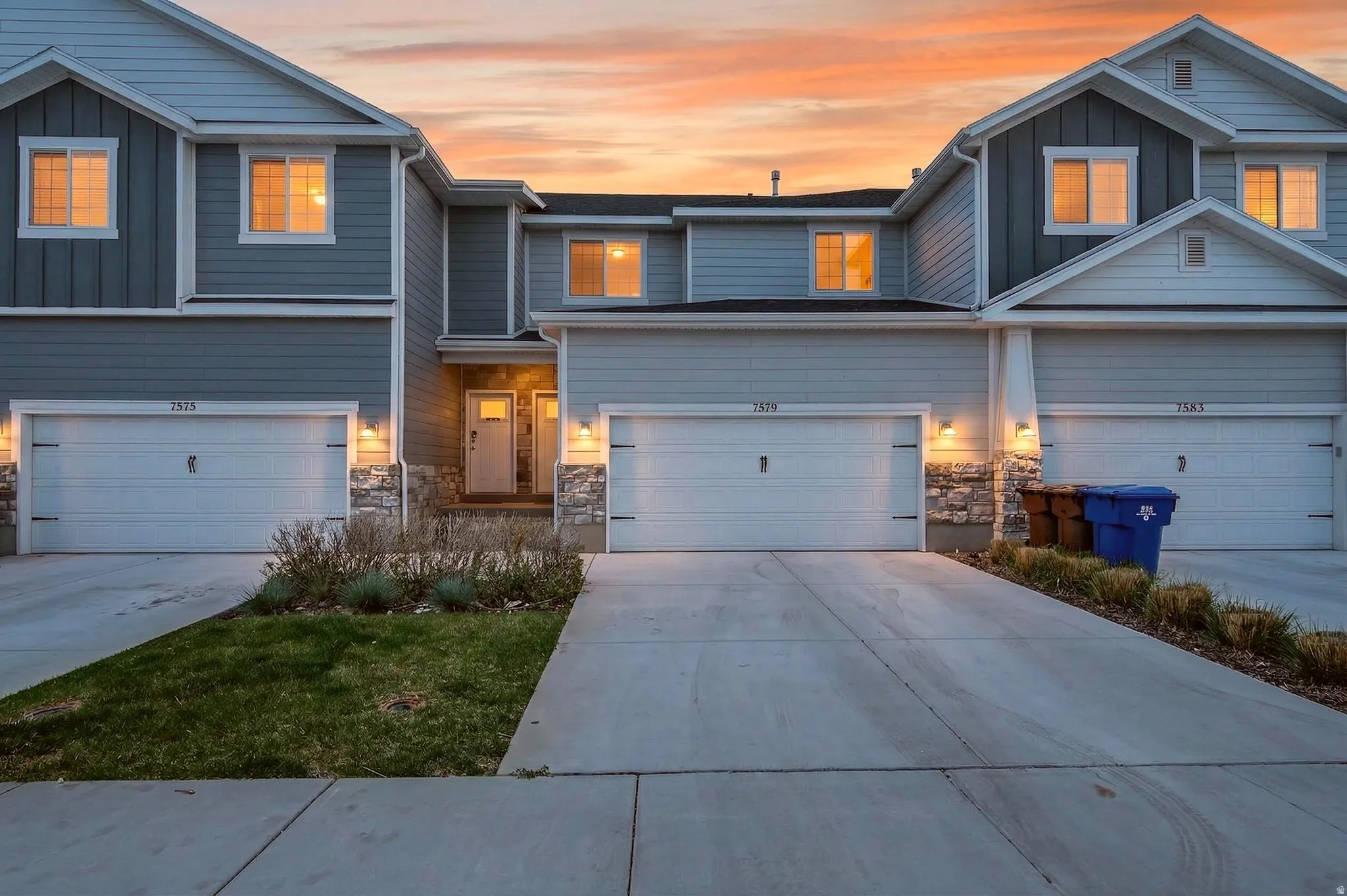 View of front facade featuring board and batten siding, stone siding, concrete driveway, and a garage