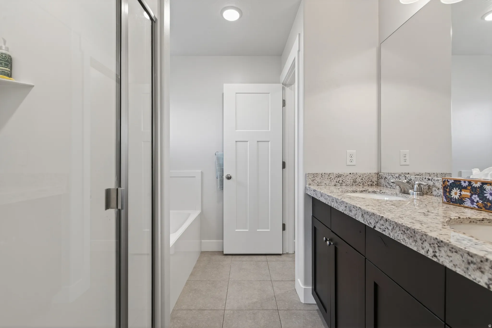 Full bathroom featuring a garden tub, double vanity, a shower stall, and light tile patterned floors