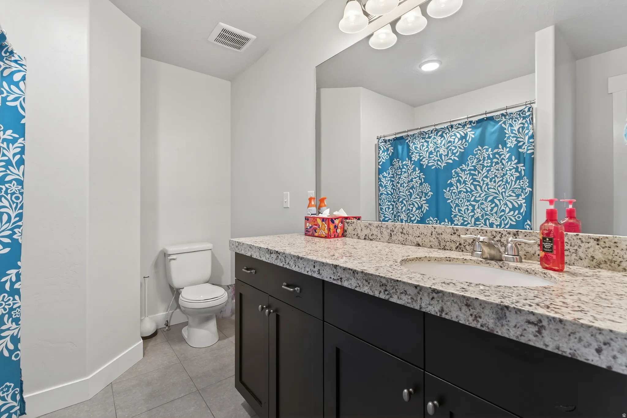 Full bathroom featuring a shower with shower curtain, vanity, and light tile patterned floors