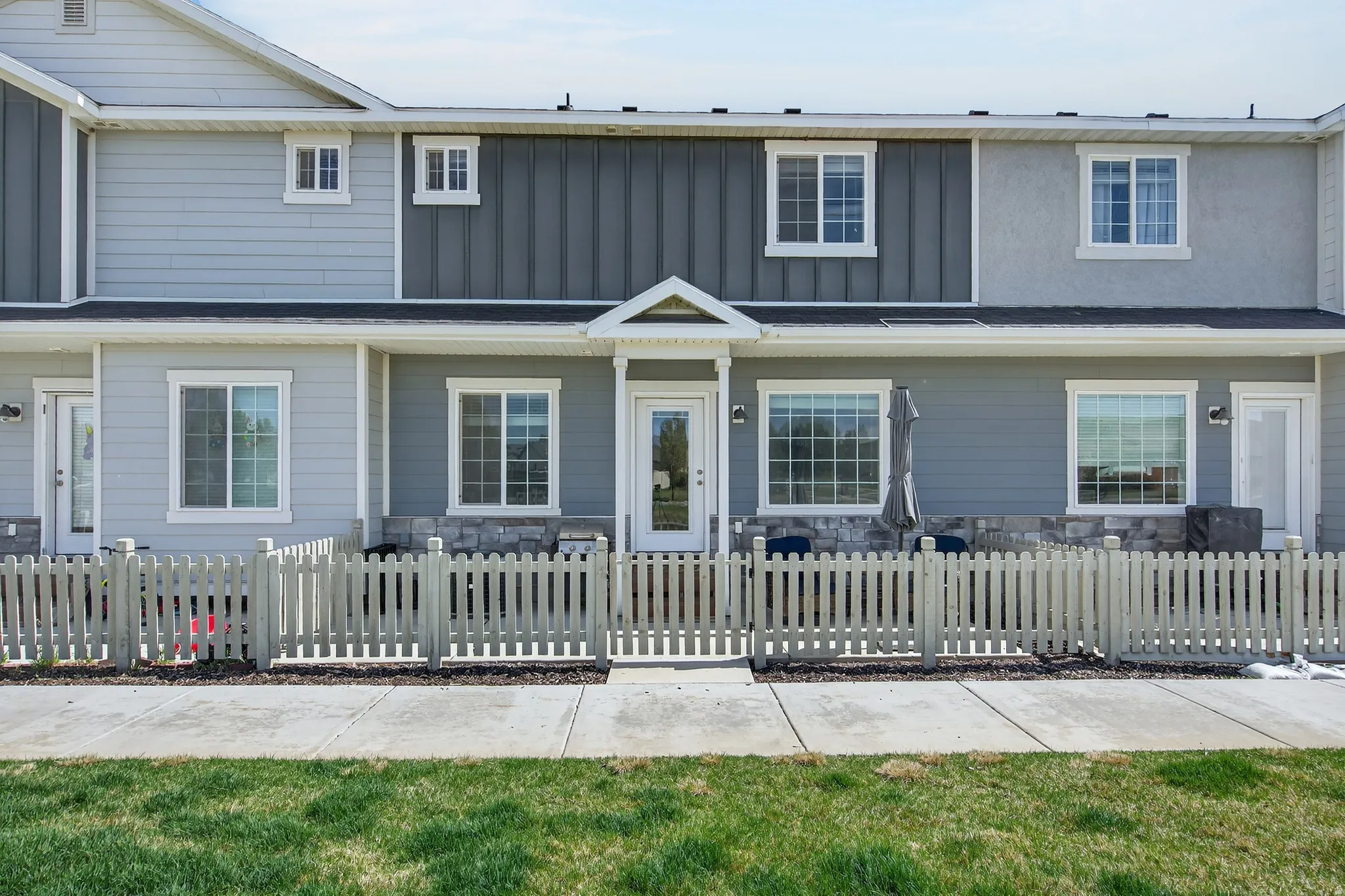 Traditional home featuring stone siding, board and batten siding, and a fenced front yard