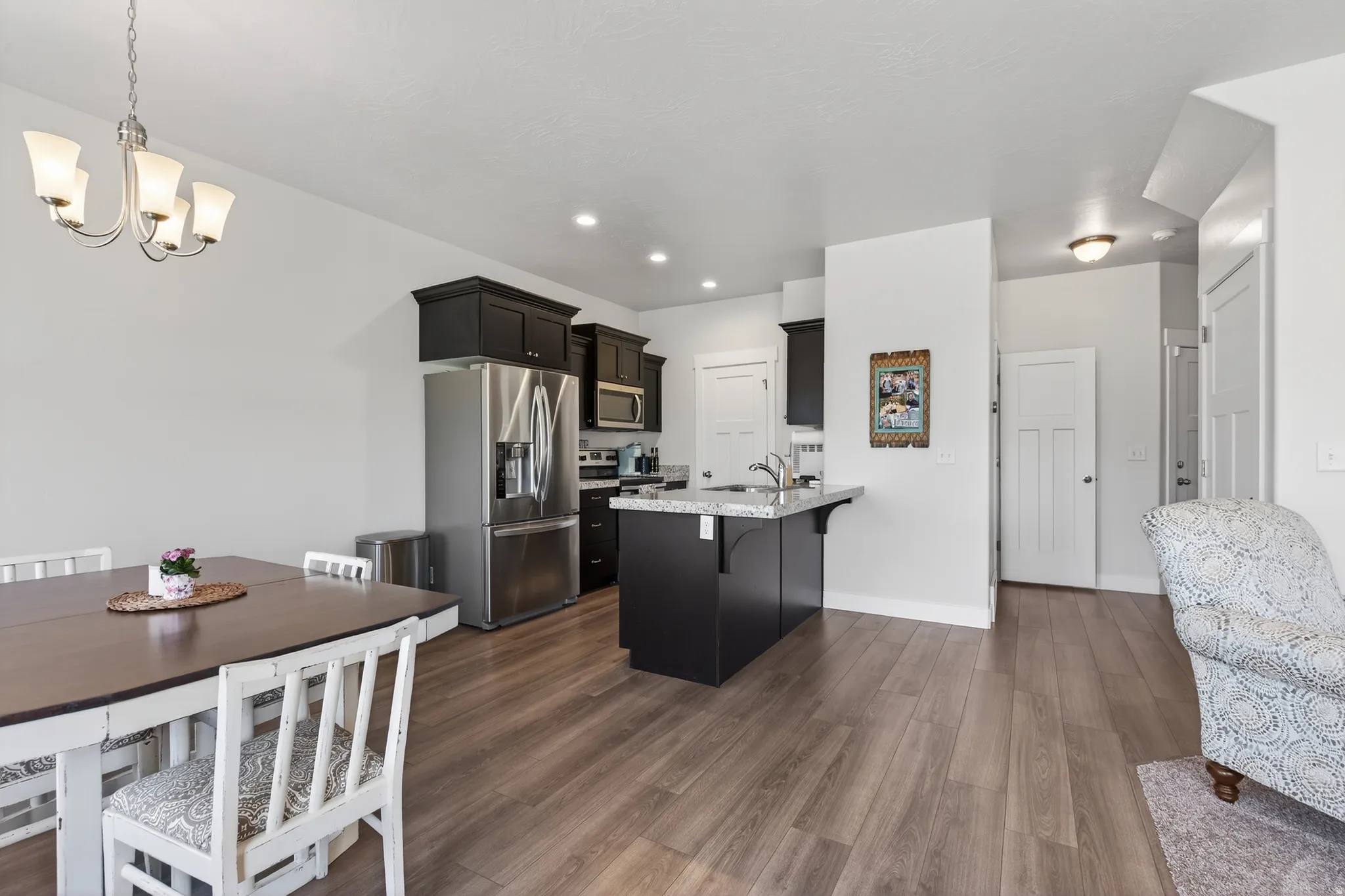 Kitchen featuring a kitchen bar, stainless steel appliances, dark wood finished floors, a peninsula, and suspended lighting