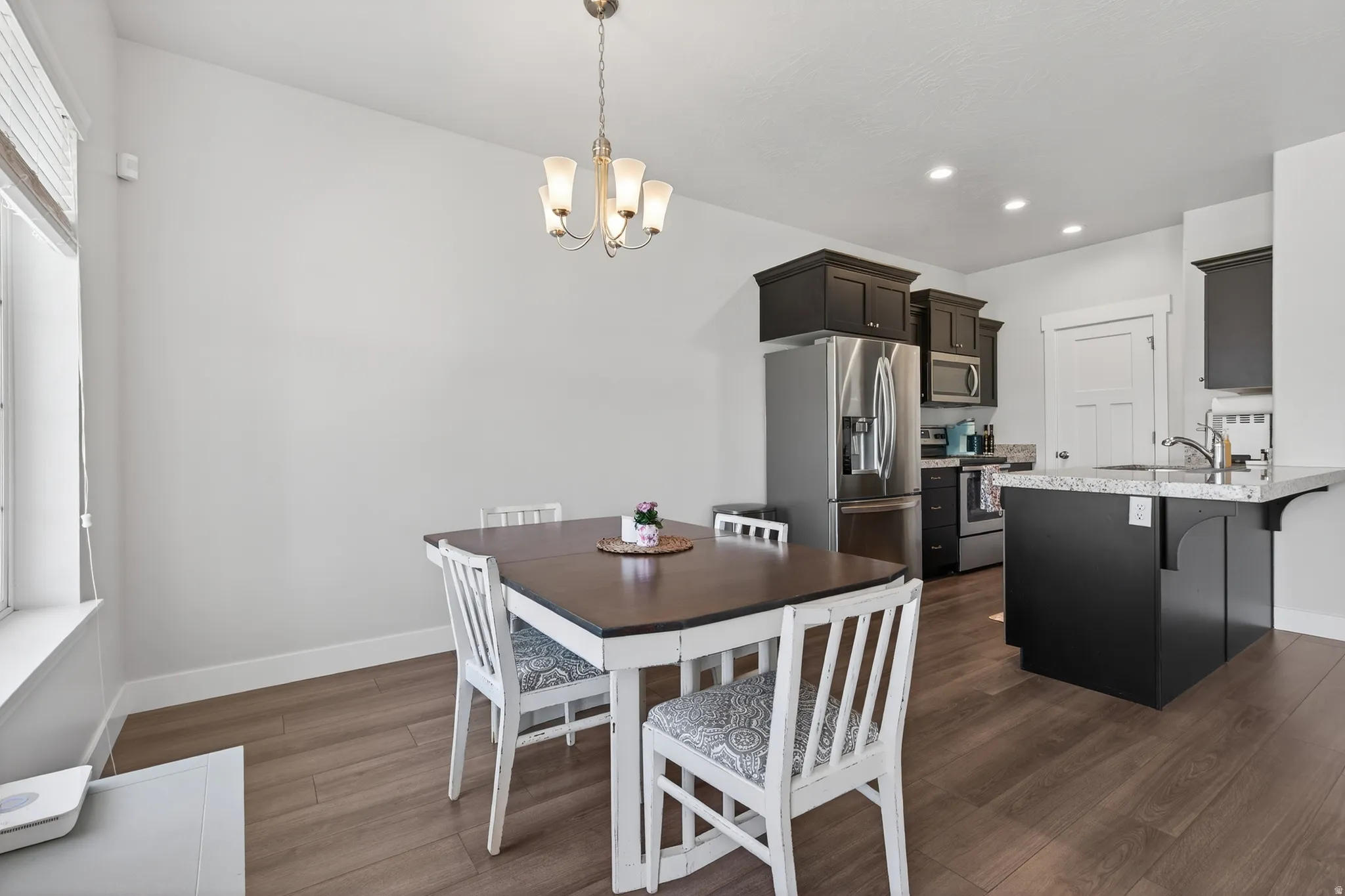 Dining space with dark wood-style floors and suspended lighting