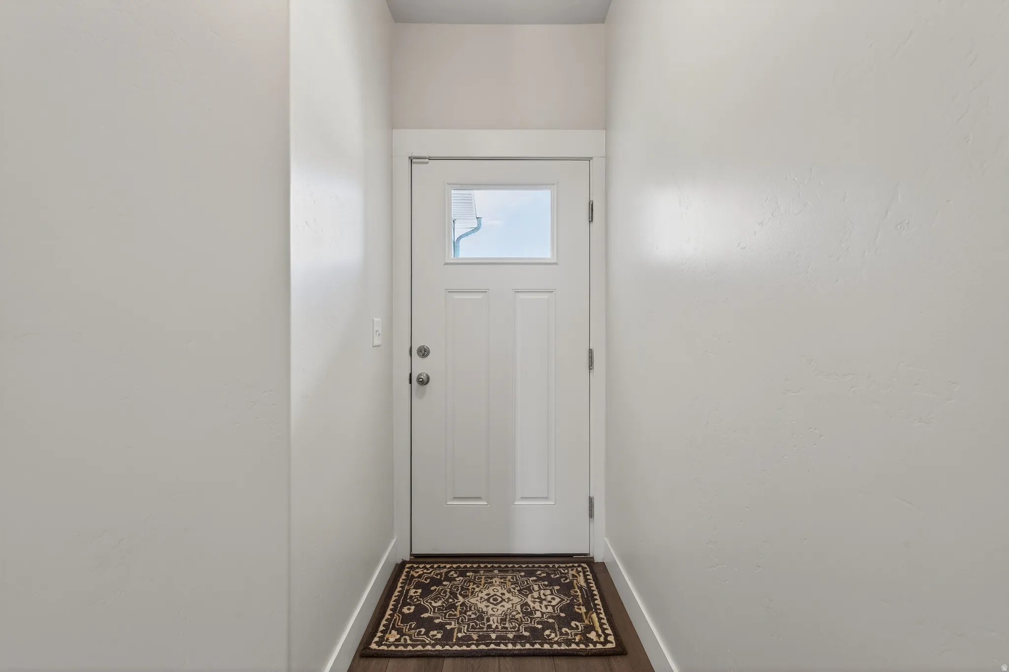 Doorway to outside with baseboards and wood finished floors