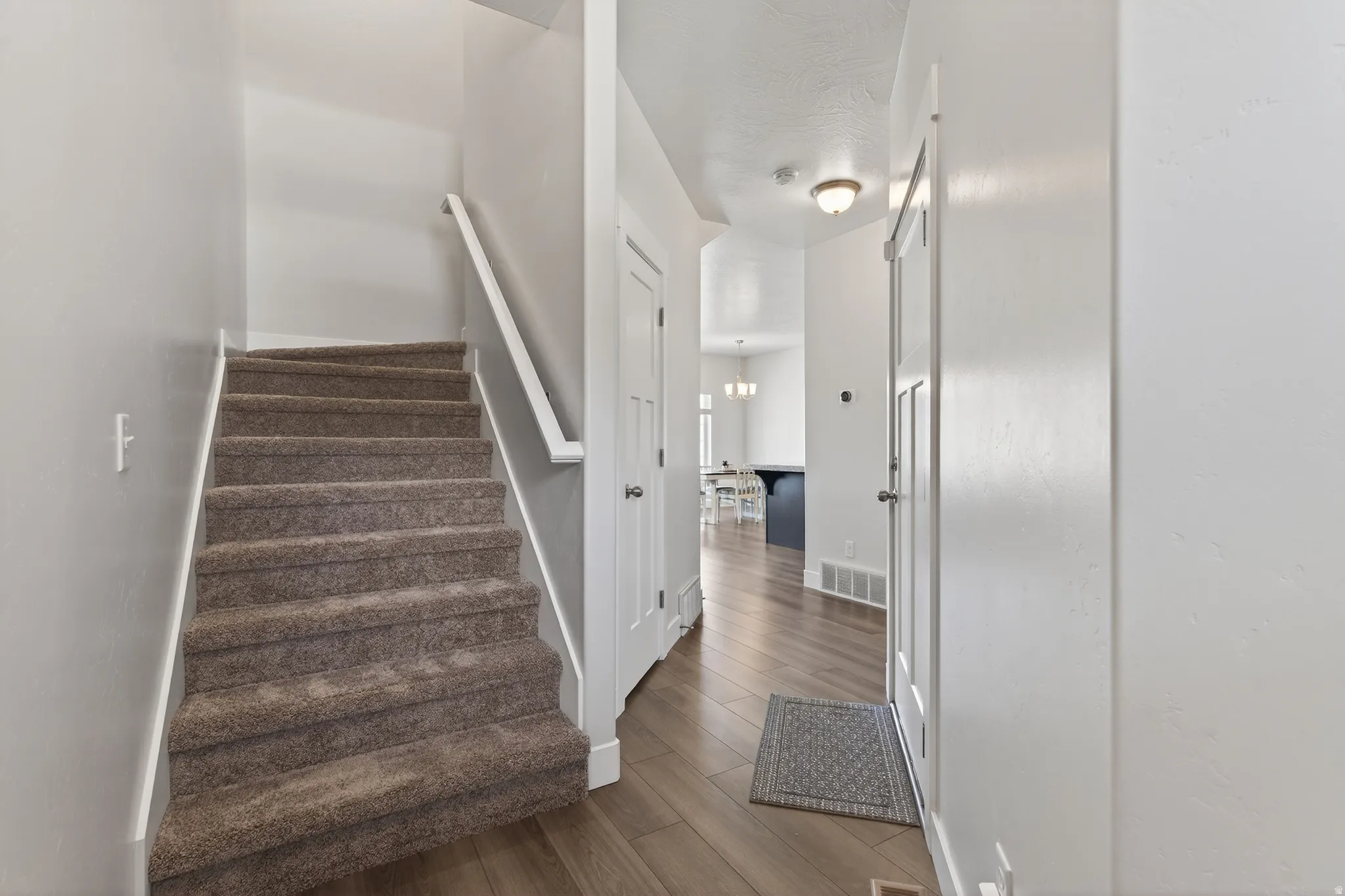 Stairway with wood finished floors and hanging lights