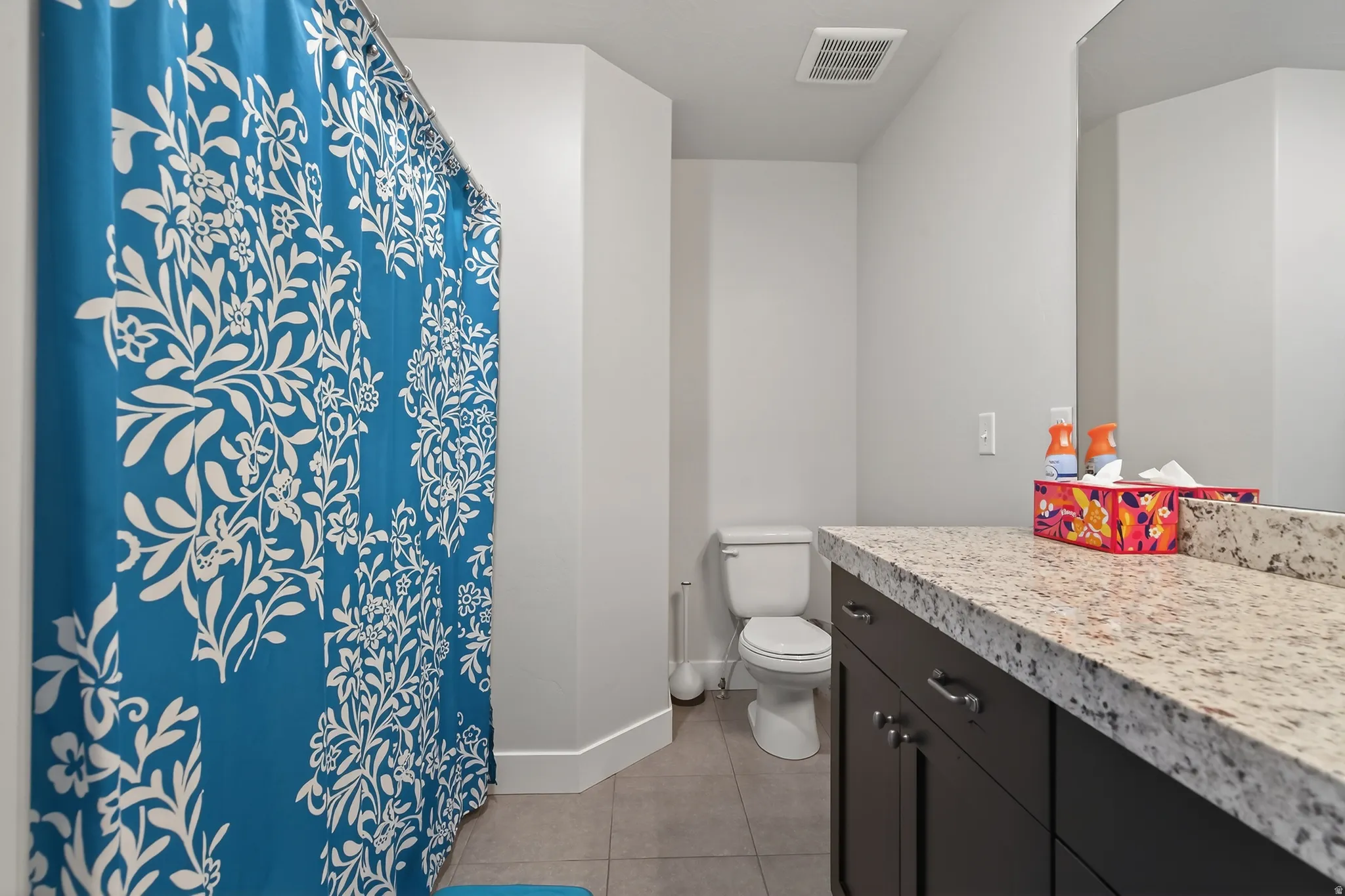 Bathroom featuring curtained shower, vanity, and light tile patterned flooring