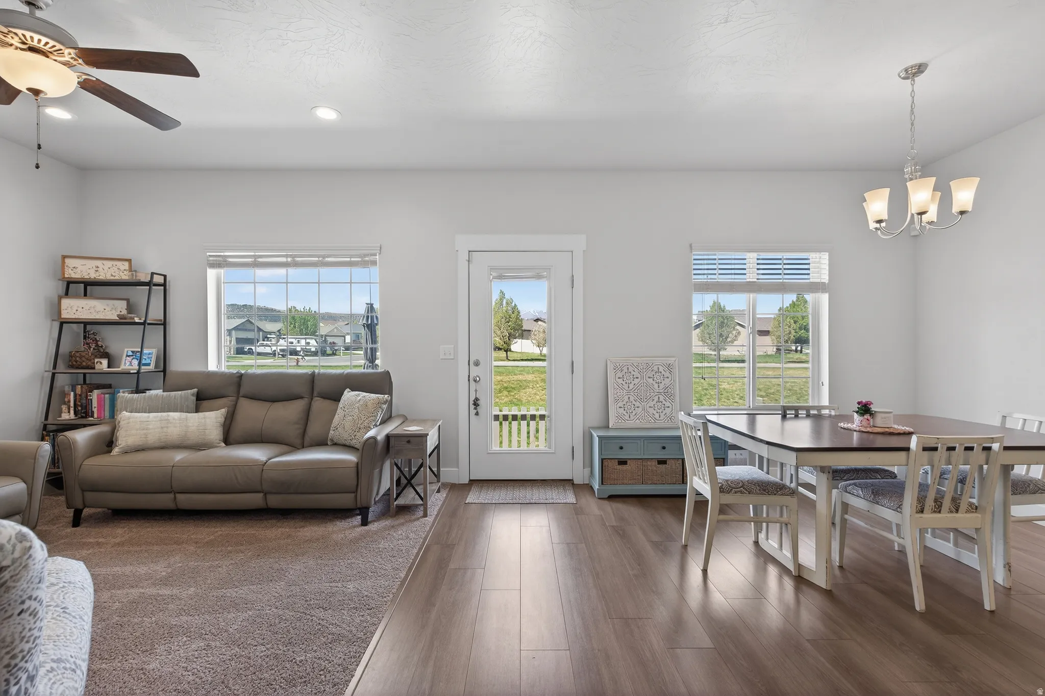 Living room with dark wood-style flooring, ceiling fan, and suspended lighting