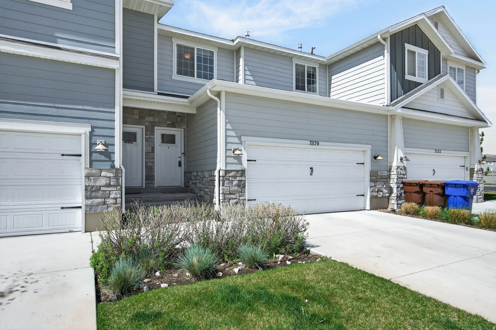 View of front of house featuring stone siding, concrete driveway, and a garage