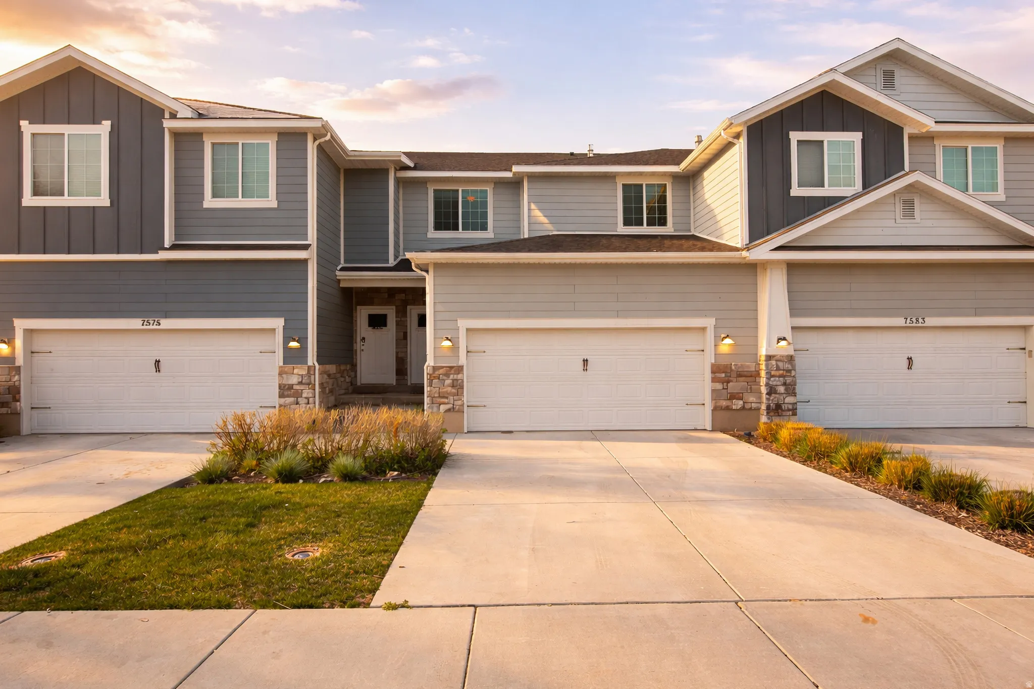 Craftsman house featuring board and batten siding, driveway, stone siding, and an attached garage