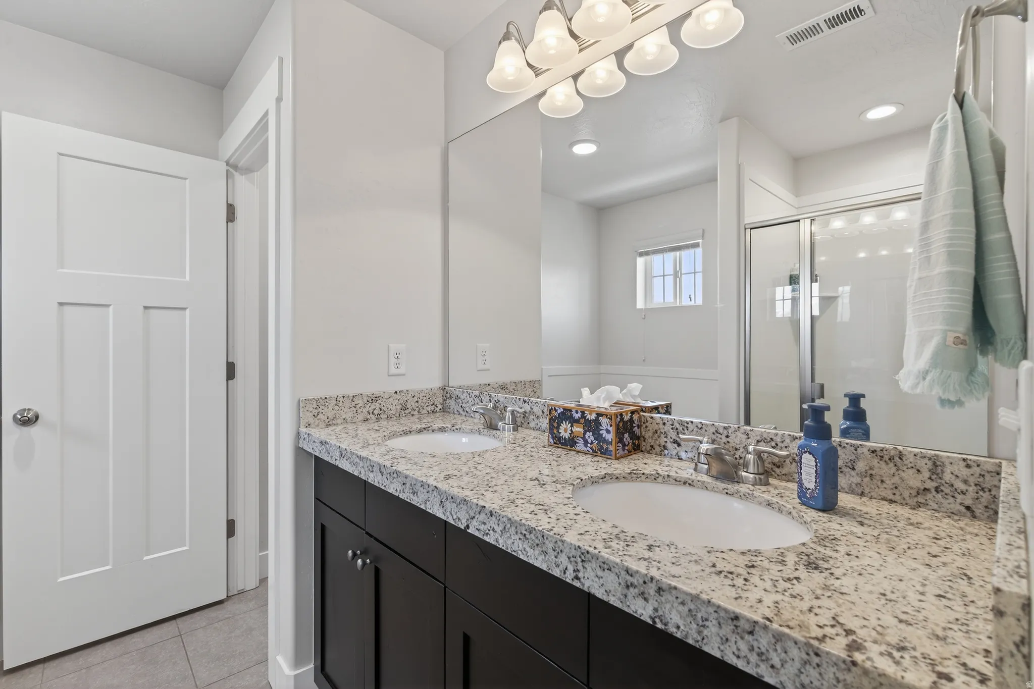 Bathroom with double vanity, a stall shower, and light tile patterned floors