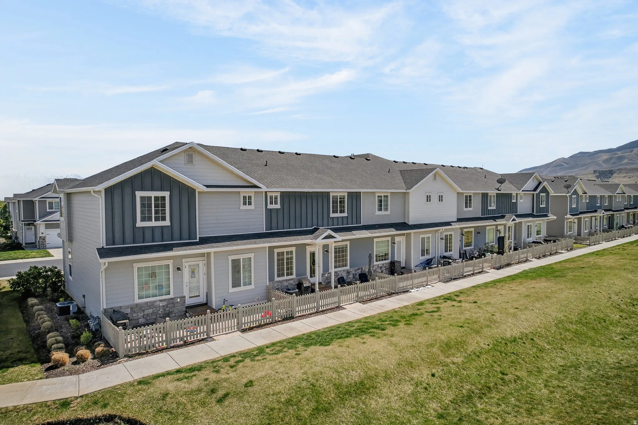 Back of property featuring board and batten siding, a residential view, a fenced front yard, and stone siding