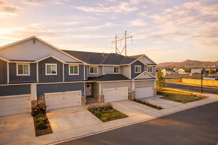 Craftsman house with stone siding, board and batten siding, driveway, a residential view, and an attached garage