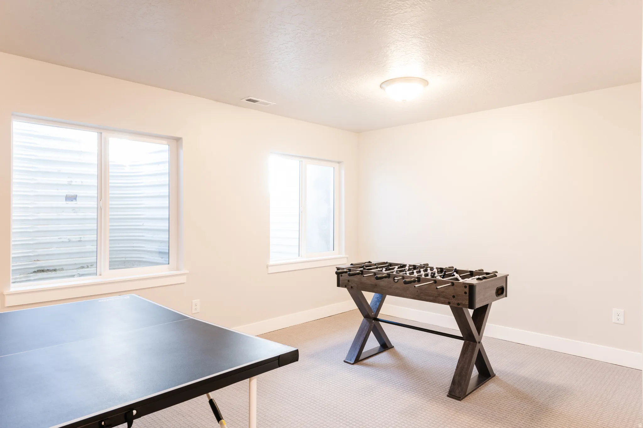 Rec room featuring light colored carpet and a textured ceiling